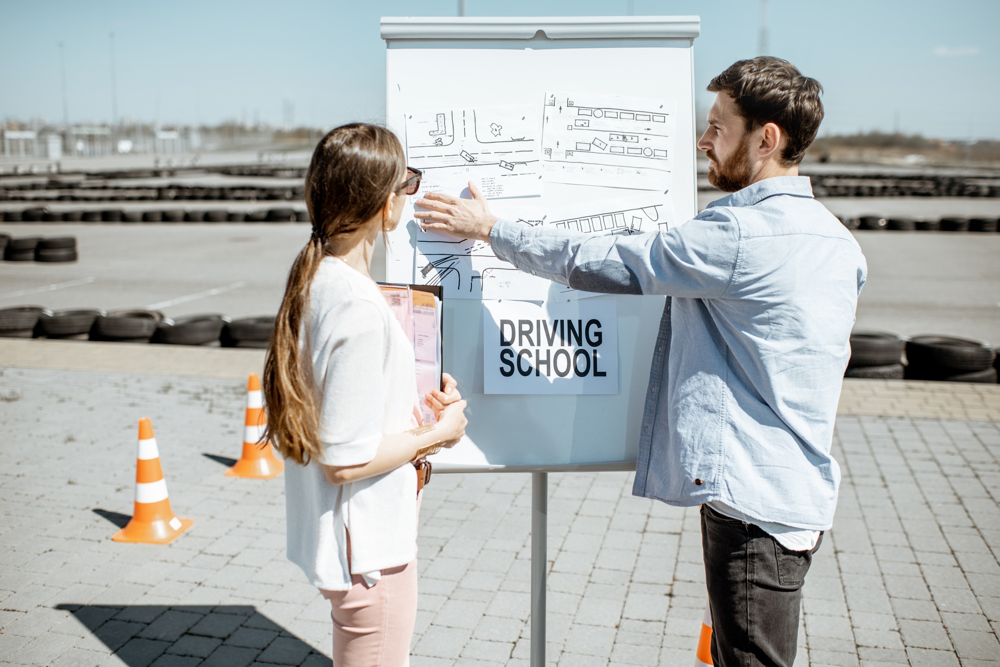Instructor showing traffic shemes to a female student outdooors