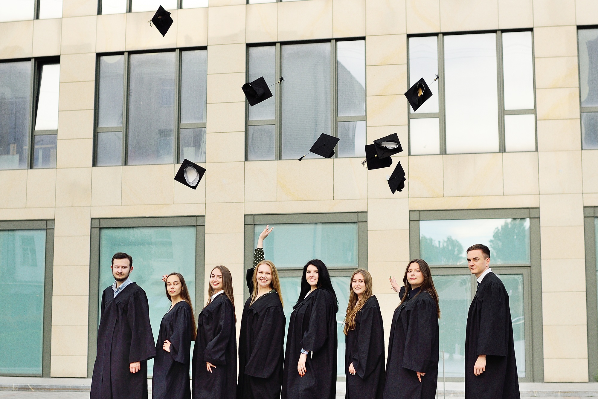 students in robes throw up academic caps and are happy to receive higher education